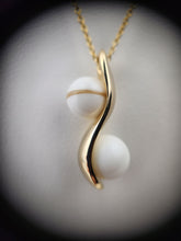 Charger l'image dans la galerie, Gros plan d'un élégant collier à pendentif en joaillerie fine MONA présentant un motif torsadé doré avec deux perles rondes sur un fond sombre.