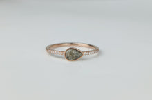Charger l'image dans la galerie, La Bague Goutte de vie de MONA fine joaillerie est ornée d'une pierre centrale grise mouchetée en forme de poire, rehaussée de zircons le long de la bande, sur fond blanc.