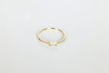 Charger l'image dans la galerie, Une délicate bague en or avec une pierre centrale rectangulaire au centre, flanquée de petites pierres rondes incrustées dans l'anneau. Le fond est blanc uni. Il s'agit de la Bague Livia de MONA fine joaillerie.