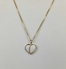 Charger l'image dans la galerie, Un délicat collier chaîne en or 10 carats de MONA fine joaillerie, nommé Pendentif Nourri-Source 12 mm, présentant un design élégant de deux contours de cœur entrelacés. Le collier est placé sur un fond uni de couleur claire, mettant en valeur ses inclusions exquises.