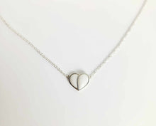Charger l'image dans la galerie, Un délicat collier en argent, le "Collier Nourri-Source 10mm", de MONA joaillerie fine. Le pendentif présente un design minimaliste à cœur ouvert relié à une fine chaîne en argent. Le fond blanc uni souligne la simplicité et l'élégance de ce magnifique collier sur mesure.