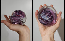 Charger l'image dans la galerie, Main d'une personne tenant un Le Cueilleur de Verre Sphère Lactée avec des motifs tourbillonnants violets et blancs, représenté sur un fond uni. La photo montre deux angles : l'un du côté de la sphère et l'autre de sa vue de dessus.