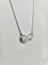 Charger l'image dans la galerie, Collier Infinity en argent avec pendentif infini de la marque MONA joaillerie fine, exposé sur un présentoir blanc.