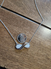 Charger l'image dans la galerie, Un délicat pendentif Collier Infinity de MONA joaillerie sur un collier en argent, un bijou raffiné, posé à côté d'une pièce de monnaie sur une surface en bois, avec la taille du bijou comparable à celle de la pièce.