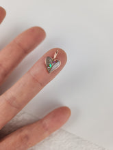 Charger l'image dans la galerie, Une main présente le Pendentif Mini Coeur de MONA fine joaillerie, un pendentif en forme de cœur aux teintes irisées, en équilibre au bout de l'index sur un fond blanc.