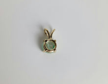 Load image into Gallery viewer, Un petit pendentif de MONA fine joaillerie, le Pendentif Solitaire Éternel, orné d'une pierre précieuse ronde vert clair sertie dans un élégant cadre en or 10 carats à quatre griffes. Le pendentif a une boucle dorée sur le dessus pour l'attacher à un collier. Le fond est blanc uni.