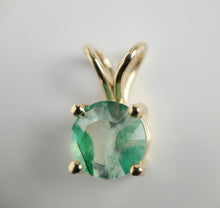 Load image into Gallery viewer, Une image en gros plan du Pendentif Solitaire Éternel de MONA fine joaillerie, comportant une pierre centrale ronde verte retenue par quatre griffes. Le pendentif en or 10 carats possède une boucle lisse et polie en haut pour l'attacher à un collier. La surface facettée de la pierre précieuse capte les reflets de la lumière, mettant en valeur son éclat.