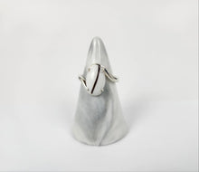 Charger l'image dans la galerie, Une bague Bague Cynthia élégante et moderne au design minimaliste, comportant une inclusion de lait maternel, présentée sur un support en forme de cône sur fond blanc par MONA fine joaillerie.