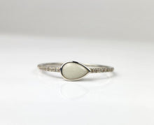 Charger l'image dans la galerie, La Bague Goutte de vie de MONA fine joaillerie est une délicate bague en argent avec un centre en forme de larme et des zircons étincelants sur une fine bande, élégamment présentée sur une surface blanche.