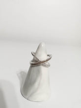 Charger l'image dans la galerie, Un présentoir conique blanc présentant deux élégantes bagues en Or 10k avec zircons couleur diamant sur un fond minimaliste.