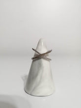 Charger l'image dans la galerie, Un cône porte-bague blanc simpliste présentant une paire de Bague Crossover croisée de MONA fine joaillerie avec des zircons étincelants de couleur diamant, sur un fond blanc épuré.