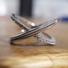 Charger l'image dans la galerie, Une élégante bague Crossover en Or 10k incrustée de zircons couleur diamant avec un design torsadé unique reposant sur une surface en bois de la fine joaillerie MONA.