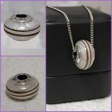Charger l'image dans la galerie, Un collage présentant un pendentif Perle européenne de Bijoux La Précieuse avec des détails métalliques et pailletés, exposé seul et accroché à une chaîne en argent, en mettant l'accent sur son design texturé et son inclusion.