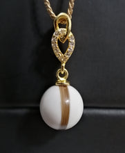 Charger l'image dans la galerie, Un élégant Pendentif Shawna en argent en or avec un accent étincelant en forme de cœur sur une pierre précieuse sphérique blanche, le tout sur un fond sombre. (Nom de marque : Bijoux La Précieuse)