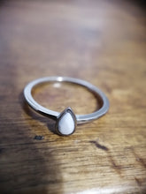 Charger l'image dans la galerie, Un gros plan d'une délicate Bague Maëva en argent avec une pierre précieuse blanche en forme de larme, posée sur une surface en bois, de MONA fine joaillerie.