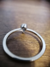 Charger l'image dans la galerie, Vue rapprochée d'une bague en argent Bague Maëva avec un seul détail en forme de cœur, posée sur une surface en bois avec un fond flou. Cette pièce exclusive est issue de la fine joaillerie MONA.