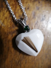 Charger l'image dans la galerie, Un Pendentif Juri blanc en forme de cœur avec une pierre précieuse verte, classée pierre de naissance, attachée à une chaîne en argent sterling 925, posée sur une surface en bois.