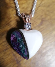 Charger l'image dans la galerie, Un Pendentif Juri en forme de cœur avec une pierre de naissance étincelante sur sa couronne, dont une moitié présente une incrustation minérale violette et verte vibrante, tandis que l'autre moitié est une surface blanche brillante, le tout suspendu sur une Bijouterie Langlois.