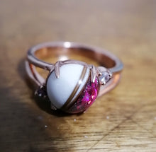 Charger l'image dans la galerie, Un gros plan d'une élégante Bague Angélique de MONA fine joaillerie avec une grande pierre blanche enfermée dans une bande en or rose avec de petites pierres d'accent.