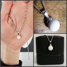 Charger l'image dans la galerie, Un collage présentant un collier en argent simple mais élégant avec un Pendentif Bélière Clara de la Bijouterie Langlois, mettant en valeur son présentoir à la main, en gros plan et niché dans un bijou noir classique.