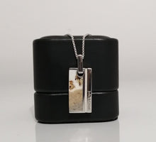 Charger l'image dans la galerie, Un pendentif homme rectangulaire 1.0 avec une image photographique et un texte, faisant partie de la collection de bijoux personnalisés de MONA fine joaillerie, suspendu à une chaîne en argent au-dessus d'une boîte à bijoux cylindrique noire sur fond blanc.