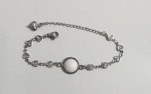 Charger l'image dans la galerie, Un délicat bracelet Bijoux La Précieuse en acier inoxydable avec une pierre centrale blanche et des petites breloques en forme de cœur.