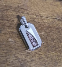 Charger l'image dans la galerie, Un pendentif Pendentif Homme 2.0 avec un incrustation d'une pierre mouchetée, posée sur une surface en bois, par MONA fine joaillerie.