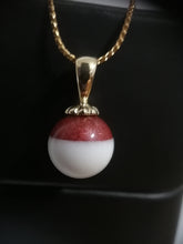 Charger l'image dans la galerie, Un élégant pendentif Bijoux La Précieuse avec une pierre précieuse ronde bicolore suspendue à une chaîne en or, exposée sur un fond sombre, créant un contraste saisissant avec un accent de perle ronde.