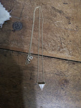 Charger l'image dans la galerie, Un délicat collier Collier Triangle fin MONA joaillerie avec un pendentif triangulaire comportant des inclusions personnalisées sur une surface en bois.