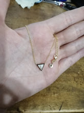 Charger l'image dans la galerie, Un délicat collier en or fin MONA joaillerie avec un pendentif Collier Triangle et une petite breloque ronde, ornée d'inclusions personnalisées, tenue délicatement dans une main ouverte.