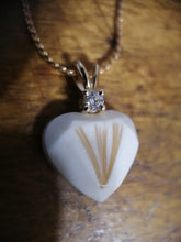 Charger l'image dans la galerie, Un élégant pendentif Juri en forme de cœur surmonté d'une pierre de naissance transparente et étincelante, accrochée à une chaîne en or sur un riche fond en bois. (Bijouterie Langlois)
