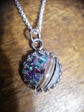 Charger l'image dans la galerie, Gros plan d'un Pendentif Griffes coloré et irisé avec inclusions de lait maternel et d'une demi-perle 12 mm sur une chaîne en acier inoxydable, posé sur une surface en bois, exposant Bijoux La Précieuse.