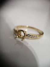 Charger l'image dans la galerie, Une élégante bague en or de MONA fine joaillerie avec une monture centrale conçue pour contenir une pierre précieuse, complétée par une rangée de diamants plus petits le long de l'anneau.