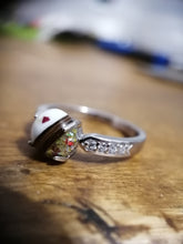 Charger l'image dans la galerie, Une élégante Bague Précieuse 8 mm de MONA fine joaillerie avec un ornement sphérique en demi-perle et or orné de zircons placés sur une surface en bois, mettant en valeur un fond bokeh qui rehausse son design délicat.