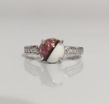Charger l'image dans la galerie, Une bague élégante avec une pierre précieuse rose entourée d'une monture blanche, flanquée d'une rangée de petits zircons transparents sur une bande argentée - la Bague Précieuse 8 mm de MONA fine joaillerie.