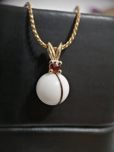 Charger l'image dans la galerie, Un élégant pendentif Pendentif Juri comportant une pierre précieuse sphérique blanche avec une singulière bande brune, accentuée par une petite pierre rouge au-dessus, gracieusement suspendue à une chaîne torsadée en argent sterling 925 sur un fond sombre. (Bijouterie Langlois)