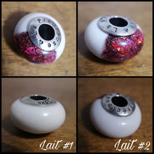 Charger l'image dans la galerie, Un ensemble de quatre images montrant un objet sphérique, une inclusion ressemblant à des Perles européennes de Bijoux La Précieuse, avec un fond rouge pailleté et un dessus blanc sur lequel est inscrit un texte, présenté sous différents angles.