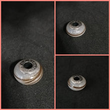 Charger l'image dans la galerie, Un collage de quatre images montrant un petit objet métallique circulaire avec un trou au centre et des marques gravées, positionné sur un fond sombre. Chaque photo présente la Perle européenne de Bijoux La Précieuse sous un angle différent, mettant en valeur ses détails complexes.