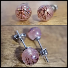 Charger l'image dans la galerie, Une paire de boucles d'oreilles sphériques infusées de paillettes avec de délicates stries de couleur, magnifiquement présentées sur un fond de grain de bois, capturant l'éclat et le design unique des bijoux fabriqués à partir de Boucle d'oreille Perles de Bijoux La Précieuse.