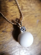 Charger l'image dans la galerie, Un élégant pendentif Pendentif Juri surmonté d'une seule pierre de naissance scintillante, suspendue à une délicate chaîne en or, reposant sur une surface en bois de la Bijouterie Langlois.