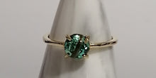 Charger l'image dans la galerie, Une bague élégante avec une pierre précieuse verte proéminente sertie dans un simple anneau en or, présentée sur un support effilé. Cette pièce est issue de notre collection "Bague Unique" de MONA fine joaillerie.
