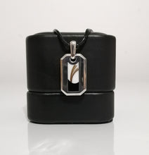 Charger l'image dans la galerie, Un élégant Pendentif Homme 2.0 argenté avec un design abstrait noir et blanc avec des inclusions personnalisées, présenté sur un support noir avec un fond blanc uni de MONA fine joaillerie.