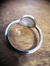 Charger l'image dans la galerie, Une bague solitaire en argent fin Bague Coupe de MONA fine joaillerie avec une seule perle ronde de 8 mm sertie dans une simple lunette, projetant une ombre sur une surface de grain de bois.