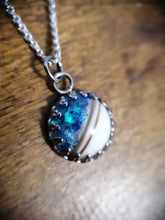 Charger l'image dans la galerie, Un pendentif irisé aux reflets bleus et verts, à moitié encapsulé par une bande blanche et orné d'une demi perle de 12 mm, est suspendu à un Pendentif Griffes de Bijoux La Précieuse.