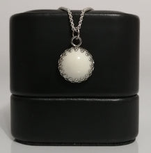 Charger l'image dans la galerie, Une photo de style minimaliste présentant un Pendentif Griffes en acier inoxydable avec une pièce maîtresse ronde en demi-perle de 12 mm entourée de petits éléments décoratifs, exposée sur un socle cylindrique noir. Nom de la marque : Bijoux La Précieuse