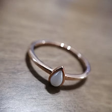 Charger l'image dans la galerie, Une délicate Bague Maëva avec une pierre en forme de poire sertie dans une fine bande, reposant gracieusement sur une surface en bois par MONA fine joaillerie.