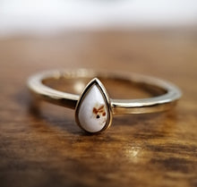 Charger l'image dans la galerie, Une élégante Bague Maëva personnalisée avec une perle en forme de larme sertie sur un anneau poli, présentée sur une surface en bois par MONA fine joaillerie.
