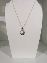 Charger l'image dans la galerie, Un élégant collier pendentif Cabella exposé, présentant un design circulaire avec une pierre précieuse centrale, présenté sur une forme de buste blanc par MONA fine joaillerie.