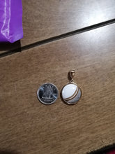 Charger l'image dans la galerie, Une pièce de monnaie et un Pendentif Cabella de MONA fine joaillerie posés sur une surface en bois.