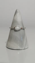 Charger l'image dans la galerie, La Bague Goutte de vie de MONA fine joaillerie présente une pierre blanche en forme de poire et des zircons étincelants sur une délicate bande d'argent, élégamment présentée sur un support en marbre lisse en forme de cône.